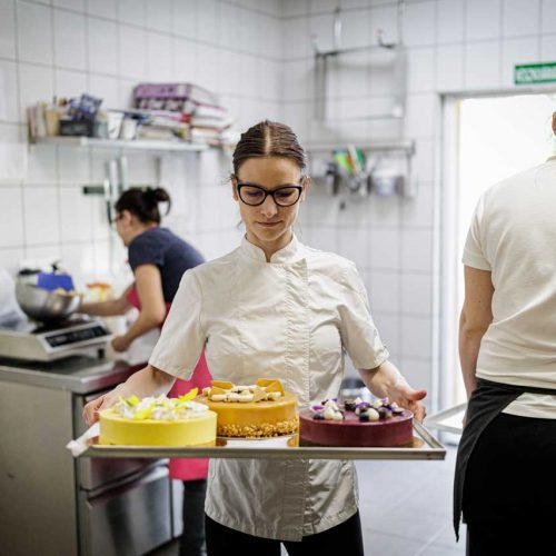 Lovász Évi a kreatív cukrász a Desszertem cukrászdában, három tortát tart a kezében tálcán